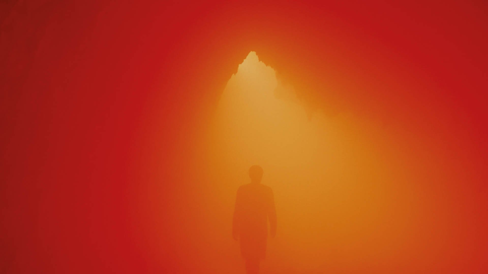 Eine Person steht uner einem Scheinwerfer. Das Bild ist komplett Orange.