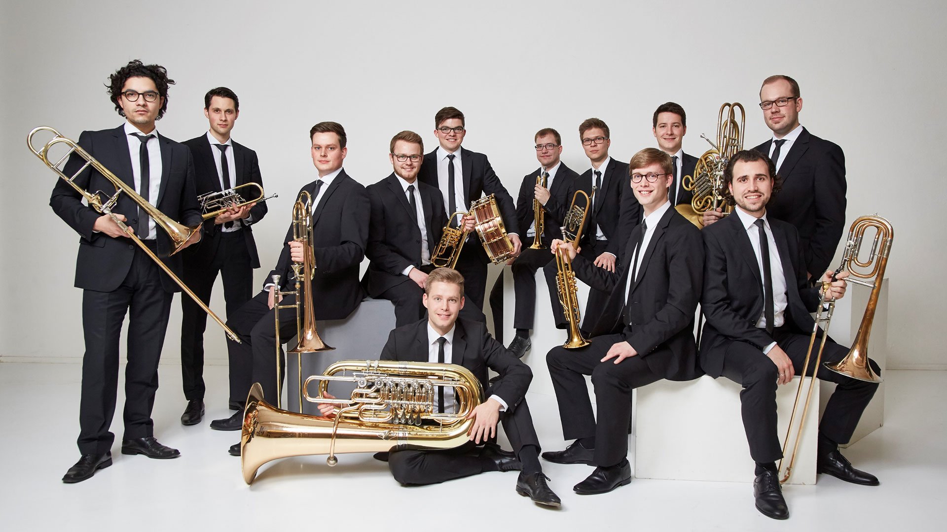 Gruppenfoto des Blechbläserensembles Salaputia Brass mit Instrumenten vor hellem Hintergrund, Werbebild zum Konzert „Winterzauber“ von Salaputia Brass.