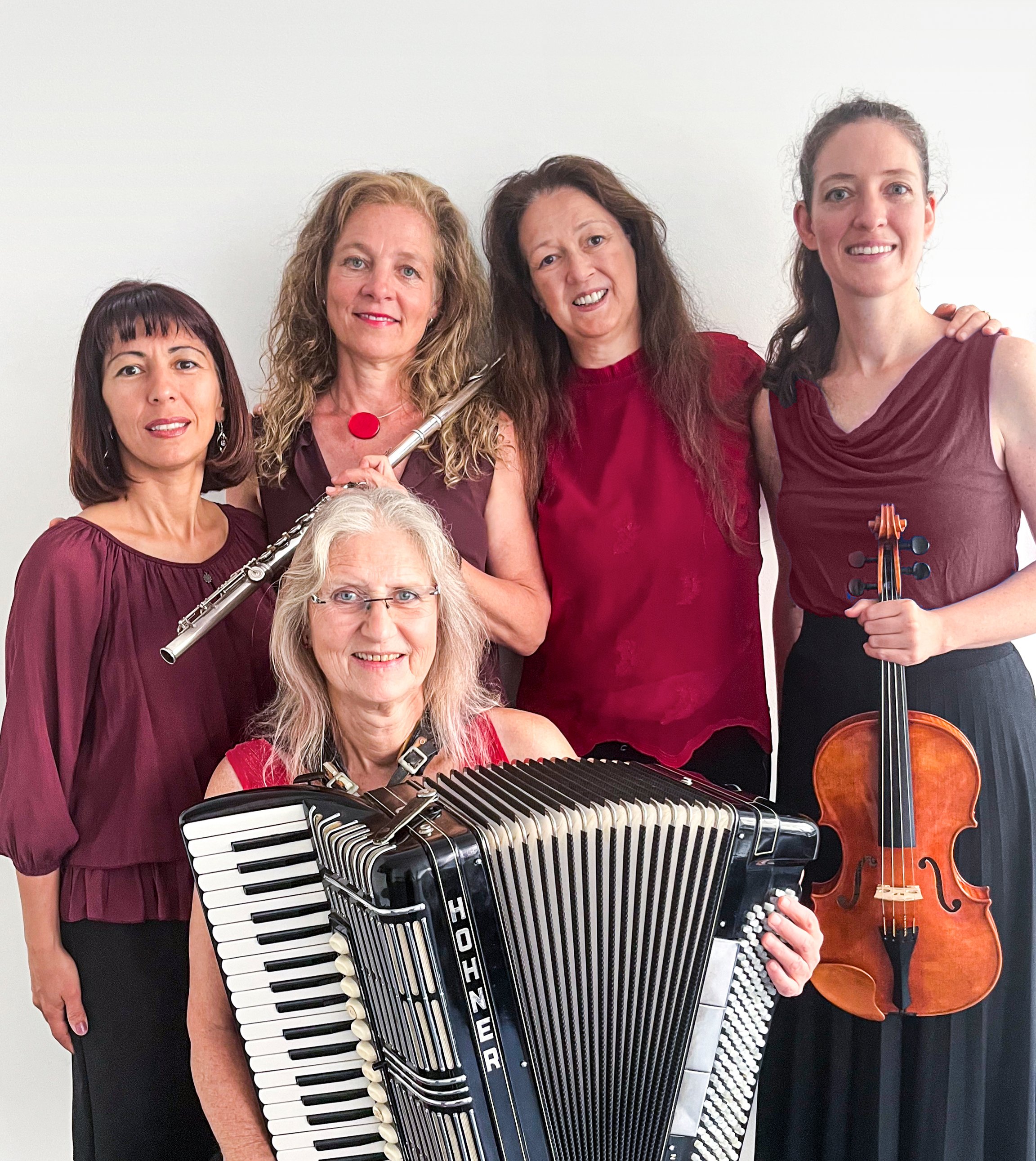 Foto von fünf Frauen mit Instrumenten vor einer weißen Wand