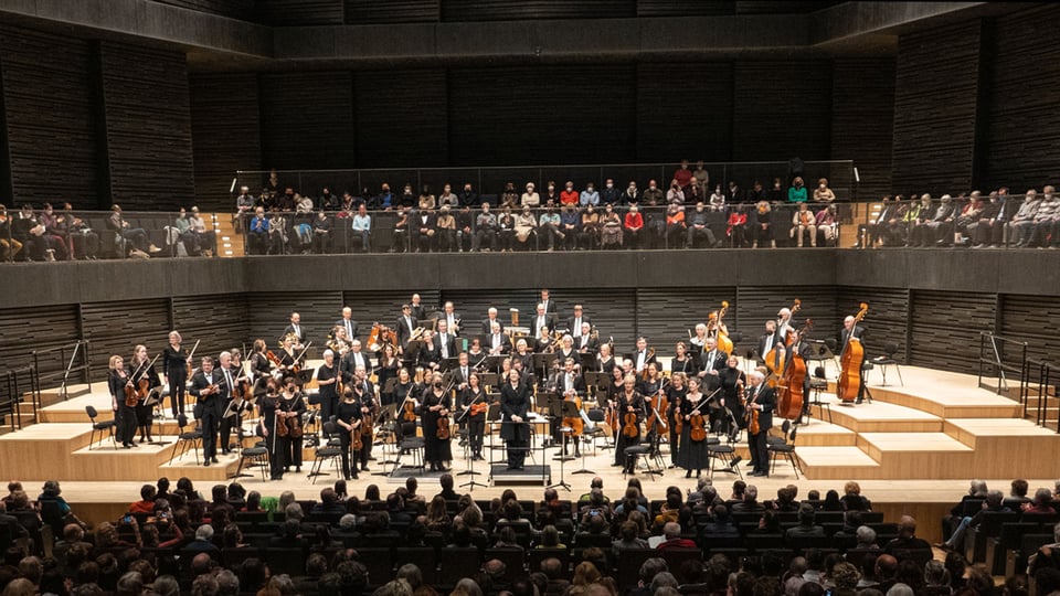 Ein Orchester auf der Bühne, im Hintergrund Publikum