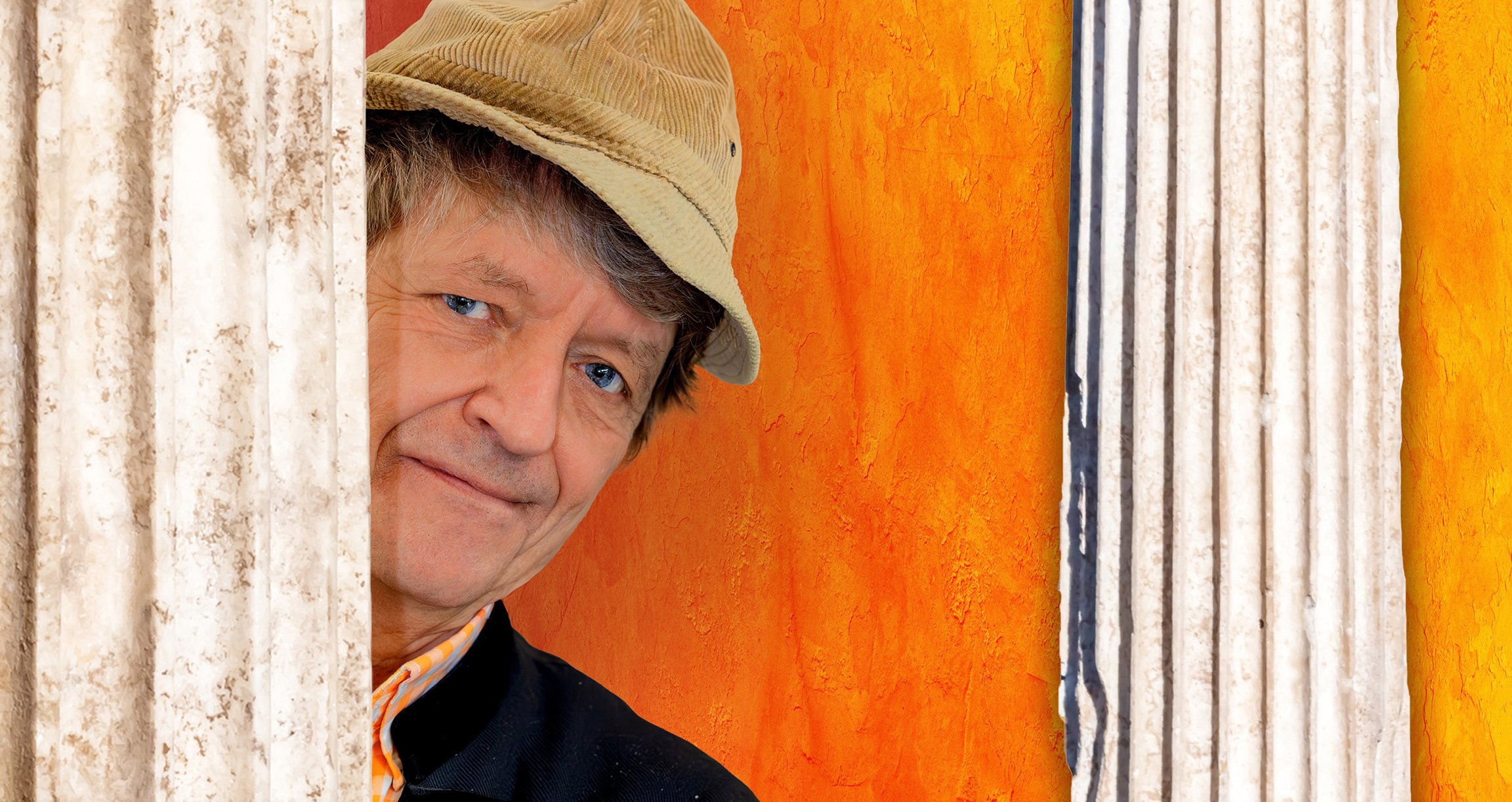 Portrait des Künstlers mit Mütze vor orangem Hintergrund