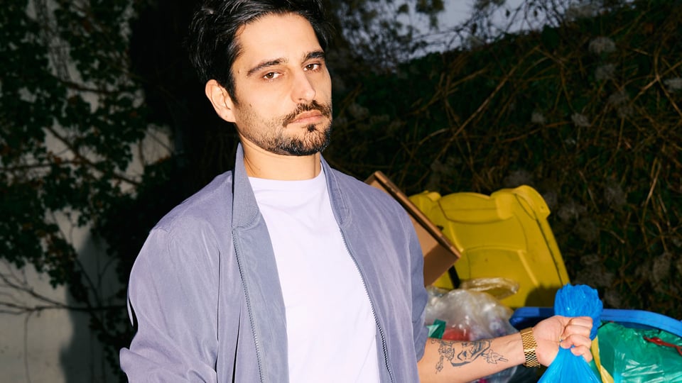 Foto für das Event Nektarios Vlachopoulos – Der beste Tag der Welt mit dem Künstler und einem Müllsack in der Hand.