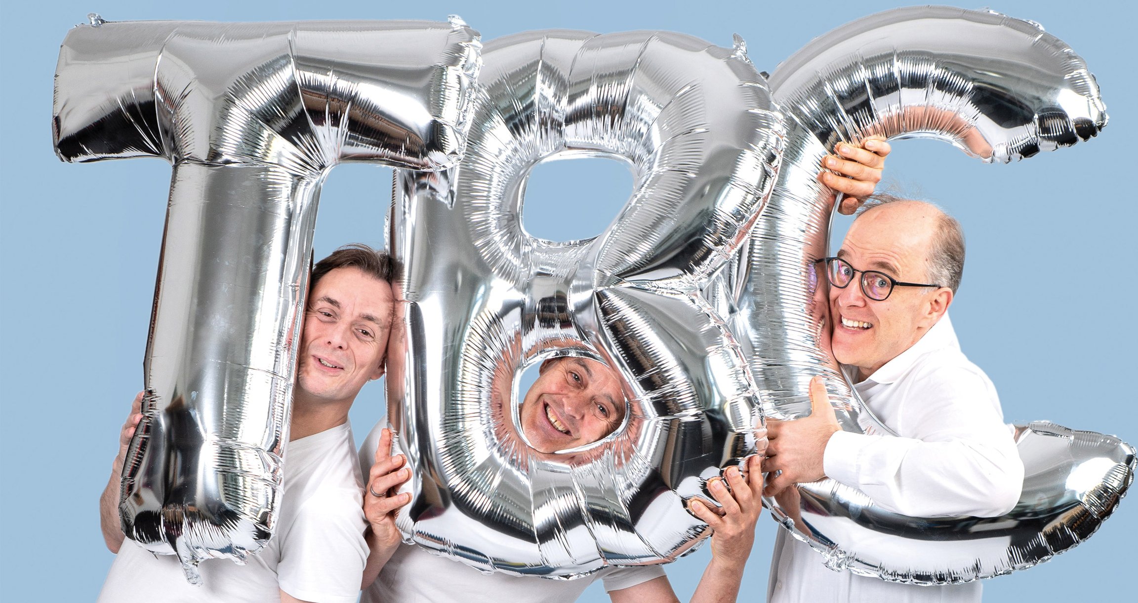 Drei Männer in weißen Hemden mit den Buchstaben T,B,C als silberne Ballons 