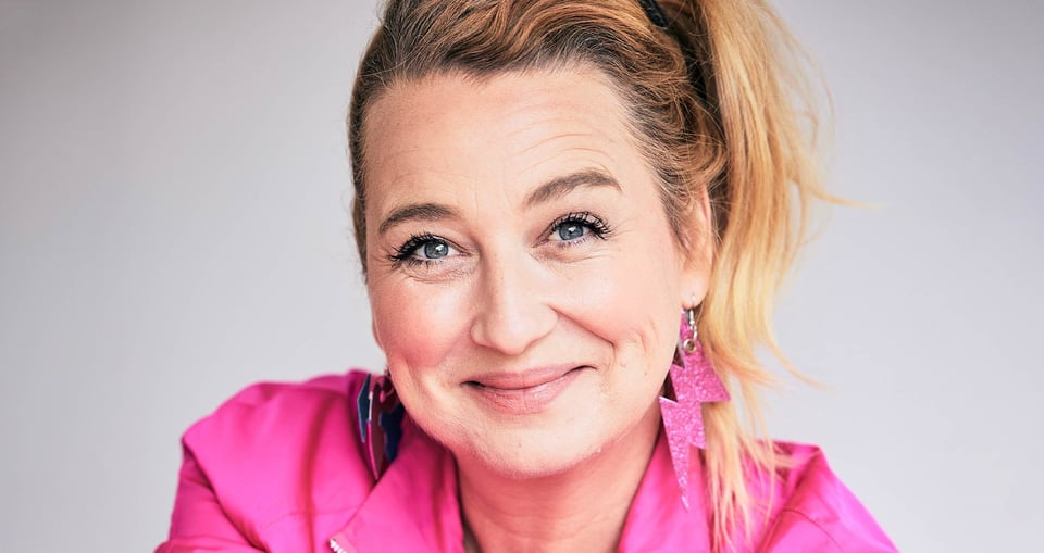 Ein Portrait von Constanze Lindner mit pinkem Oberteil und pinken Blitzförmigen Ohrringen vor weißem Hintergrund