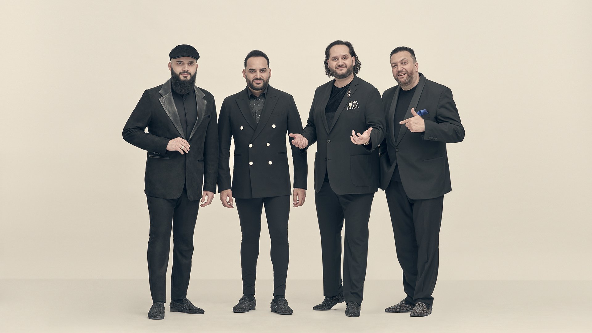 Vier Herren in schwarz gekleidet vor hellem Hintergrund