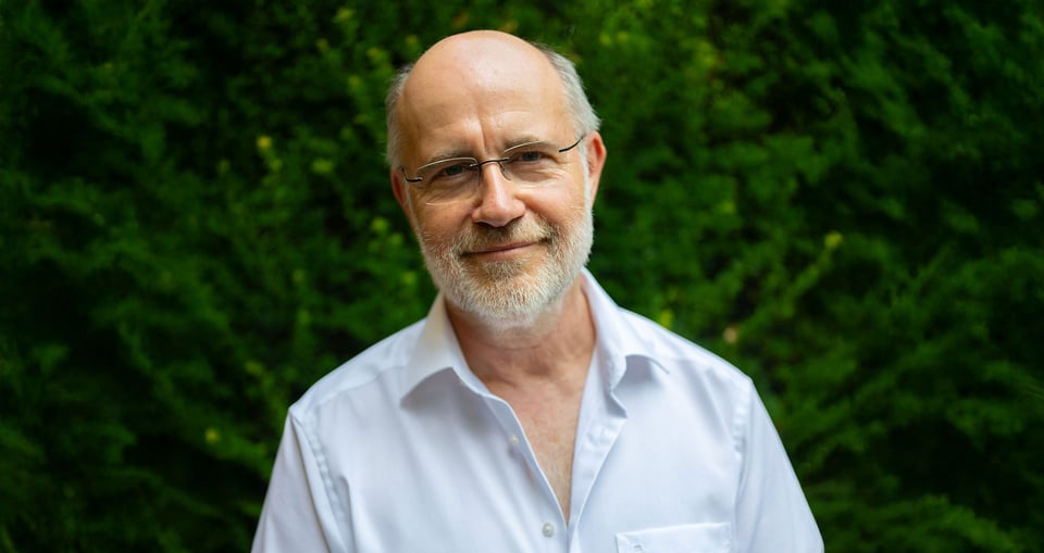 Harald Lesch steht vor einem grünen Hintergrund