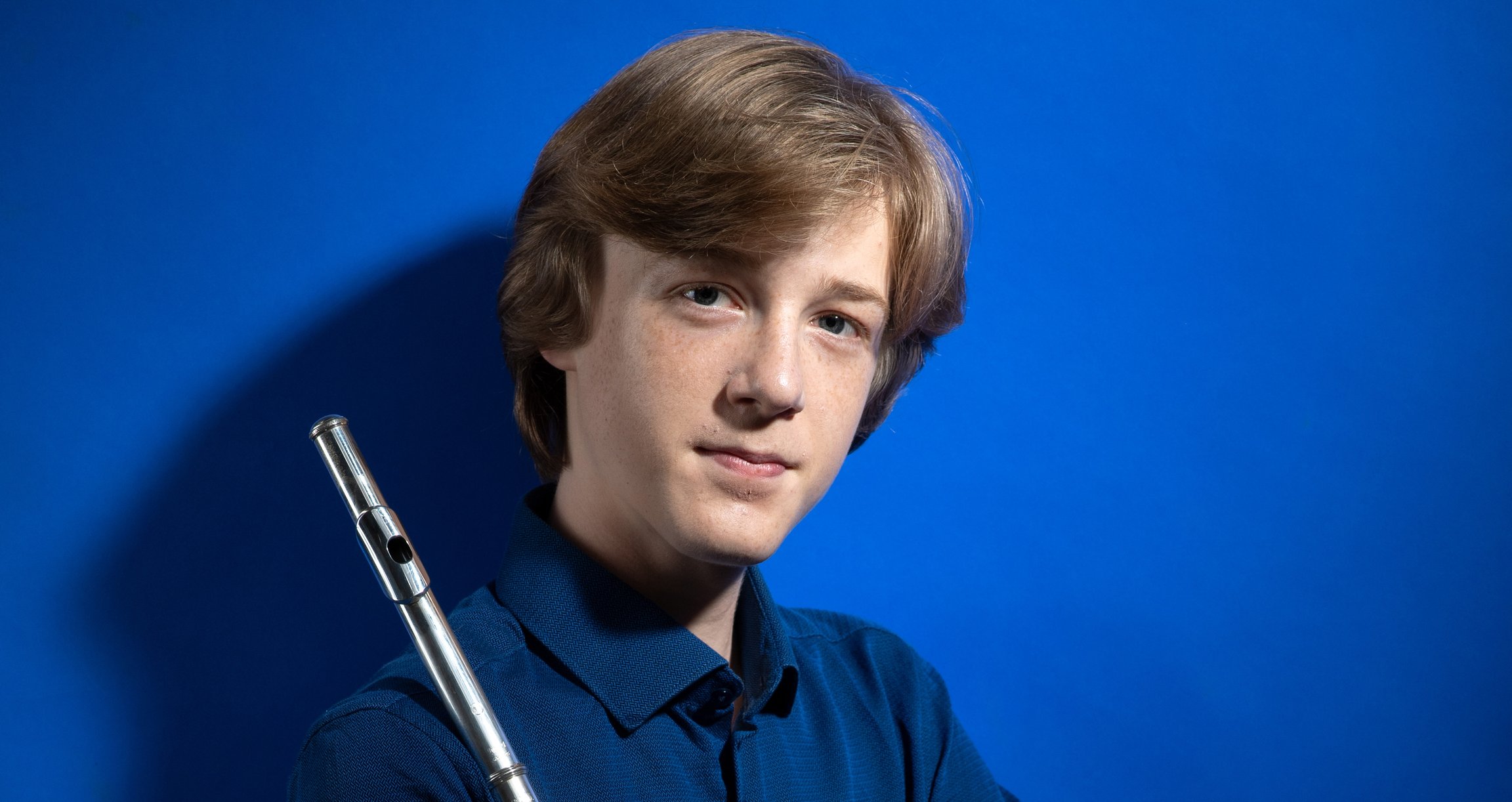 Eine Person mit Instrument in der Hand vor blauem Hintergrund
