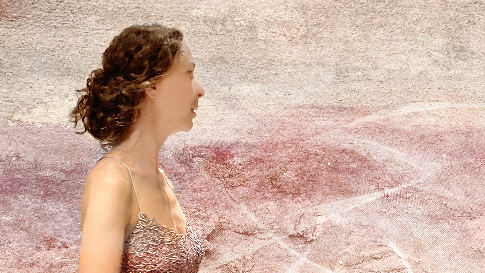 Die Künstlerin seitlich vor einer Mauer