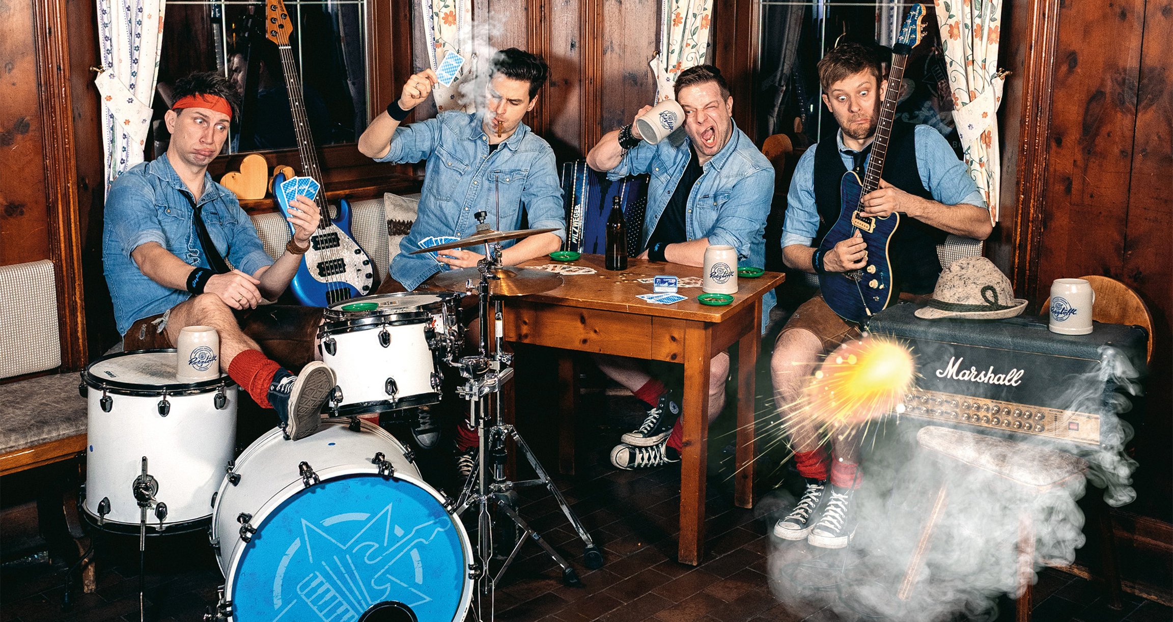 Foto der Gruppe mit Instrumenten, die an einem Holztisch sitzen, Karten spielen und Bier trinken – in einem holzvertäfelten Raum