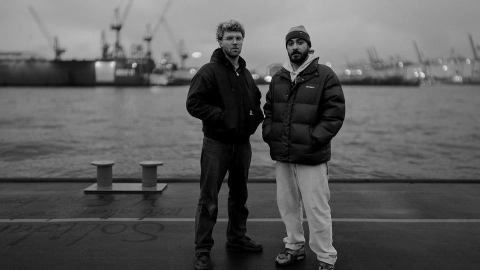Schwarz-Weiß-Foto für die Veranstaltung ‚Shkoon – Traces Tour‘ mit den beiden Künstlern in einem Hafen