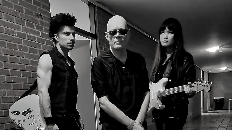 Schwarz‑Weiß‑Foto für das Event von THE SISTERS OF MERCY mit den drei Künstlern mit E‑Gitarren