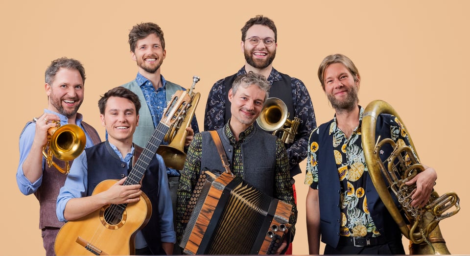 sechs Künstler die jeweils ein unterschiedliches Musikinstrument in der Hand haben vor beigen Hintergrund