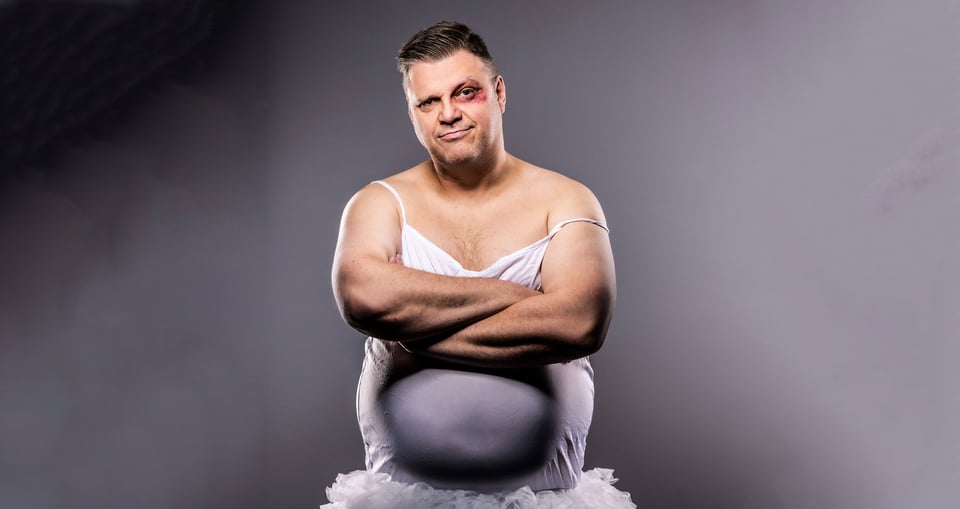 Ralf Winkelbeiner mit blutunterlaufenem Auge in weißem Ballett-Kleid mit grau-nebligem Hintergrund