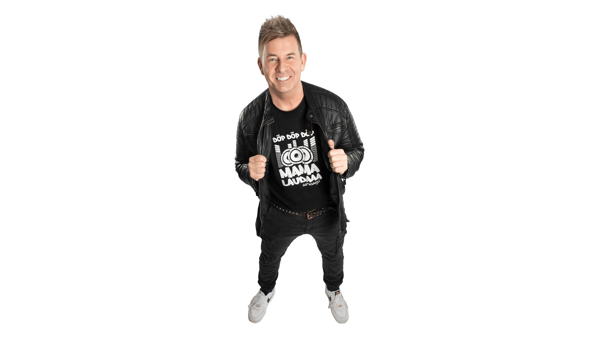 Person in schwarzer Lederjacke und Shirt mit dem Schriftzug Mamma Lauda steht in dynamischer Pose vor weißem Hintergrund; beide Hände halten die Jacke auf Brusthöhe, sportliche Schuhe und legerer Party‑Look.