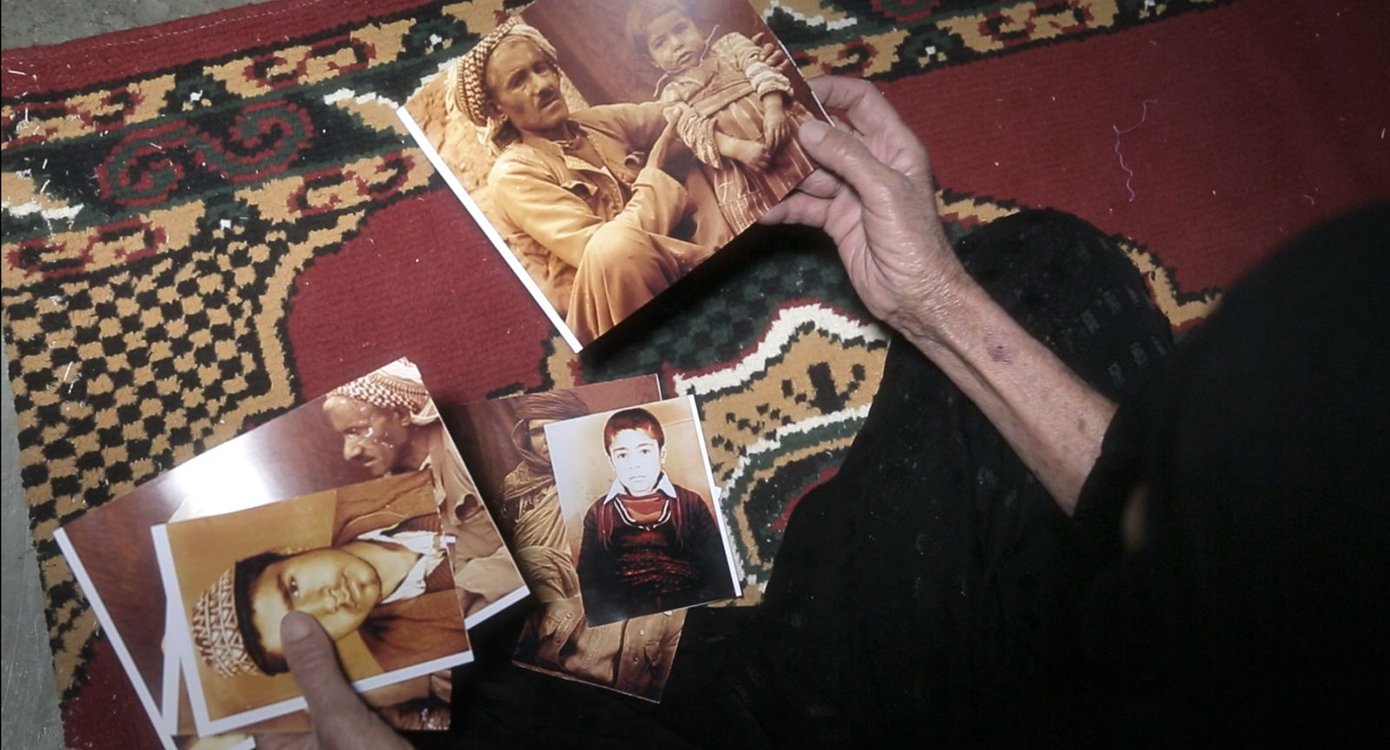 die Hände einer Person mit alten Fotos in den Händen und einem Teppich im Hintergrund.