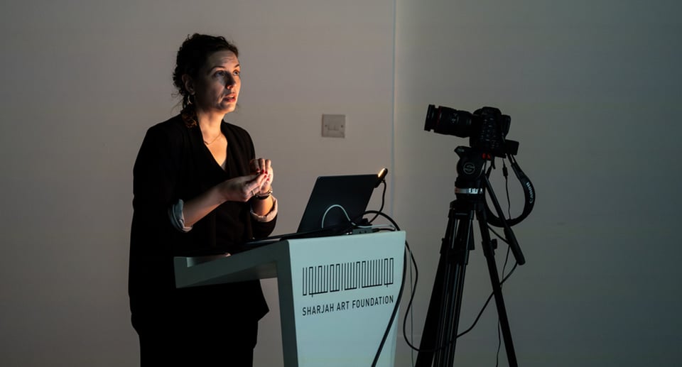 Foto einer Frau bei einer Präsentation mit Laptop und Beamer.