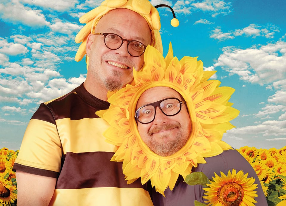 Foto der beiden Künstler – einer als Biene, der andere als Sonnenblume verkleidet.