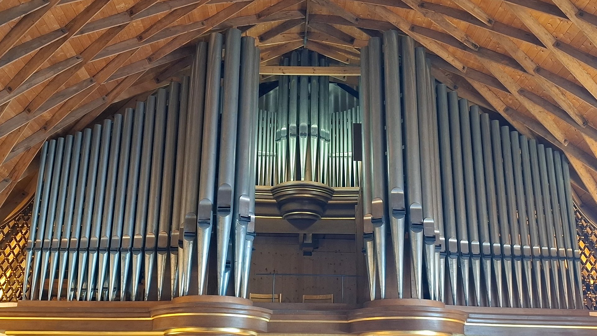 Große Kirchenorgel mit Metallpfeifen unter hölzernem Dachstuhl zur Veranstaltung Klangbrücken Orgelkonzert mit Anian Wiedner