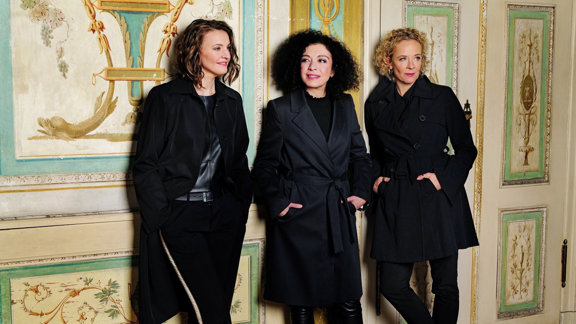 Foto für das Event „Karneval des Glücks“ – drei Frauen lehnen an einer Wand.