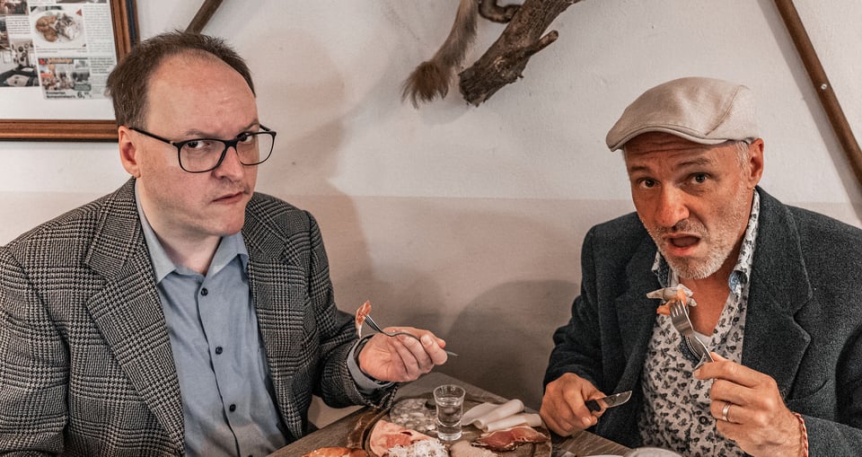 Zwei Herren sitzen an einem Tisch und essen