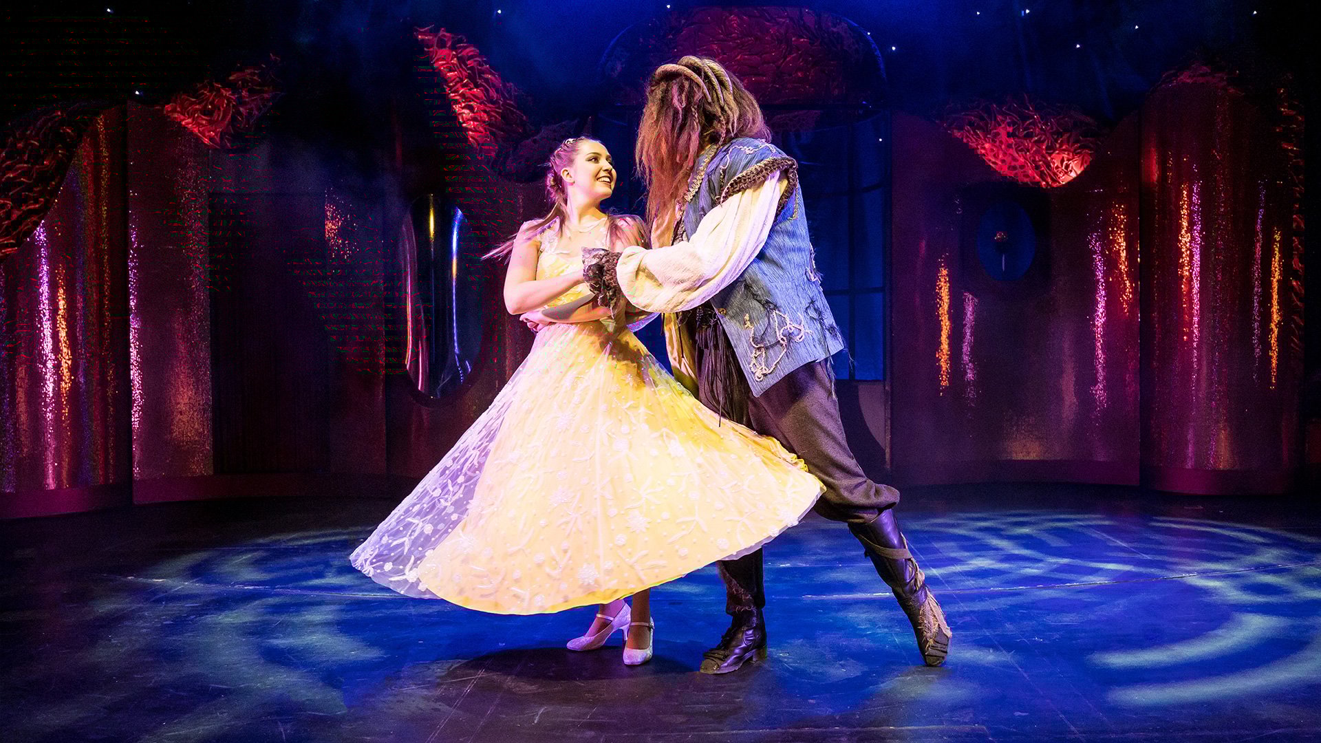 Ein Foto vom Event ‚Die Schöne und das Biest – das Musical‘ mit den Figuren von Belle und Biest beim Tanzen