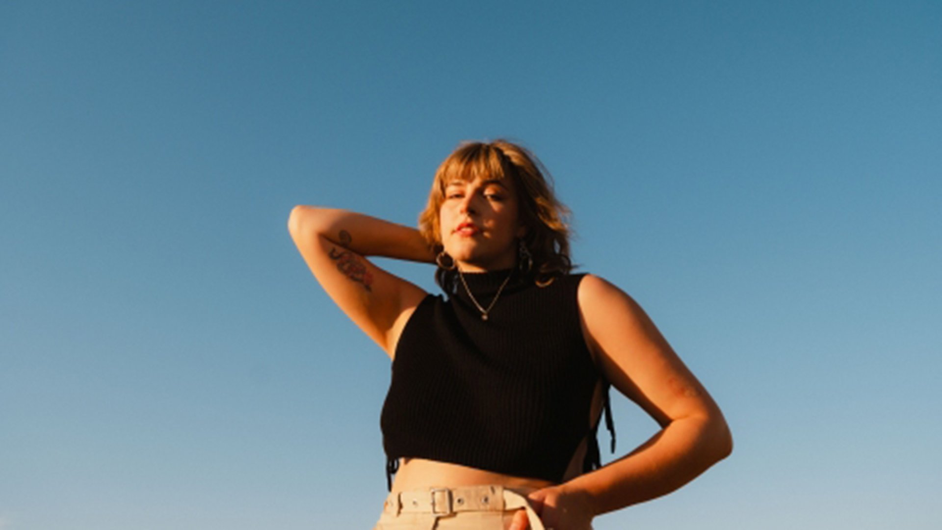 Eine Dame mit schwarzem Oberteil vor hellblauem Himmel