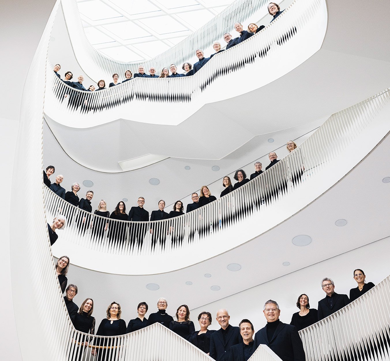 Chor in dunkler Kleidung auf Wendeltreppe über drei Etagen 