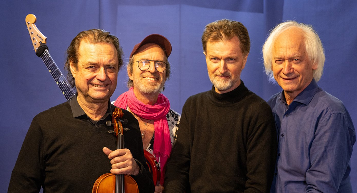 Vier Herren, zwei mit Instrumenten, vor blauem Hintergrund